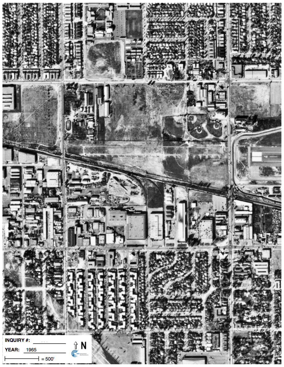 A 1965 black and white aerial survey photograph of an industrial and residential district, used for forensic land use analysis.